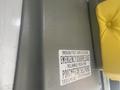 A grey panel with an emergency door release label and a yellow seat cushion on top