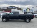 A 2010 Dodge Ram truck with a black exterior and crew cab design parked on a lot showing its side profile