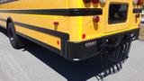 A yellow 2014 International 3000 school bus showing the rear end with lights and a black bumper featuring a chain attached