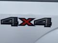 A close-up view of the 4x4 emblem on the side of a white 2017 Ford F-150