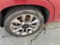 Close-up of a silver alloy wheel with a black center cap featuring the Fiat logo, mounted on a tire with visible tread and slight wear marks