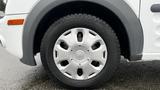 Close-up of a 2012 Ford Transit wheel featuring a silver hubcap and black tire with a textured tread pattern