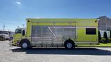 A bright yellow 1995 Freightliner FLL086 with a silver roll-up door and red accents parked on a lot