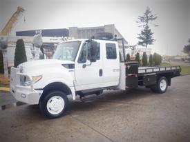 A white 2015 International TerraStar truck with a flatbed and dual rear wheels is shown from the side