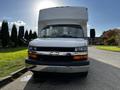 A 2015 Chevrolet Express van with a white exterior and front-facing view showcasing its grille headlights and large cabin space