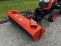 A 2018 Kubota B2650 tractor with a large orange rotary broom attachment in front equipped with blue bristles for sweeping surfaces