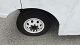 A close-up of a tire and wheel of a 2006 Ford Econoline showing the white rim with multiple lug nuts and the black tire