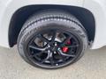 A close-up view of a black alloy wheel from a 2018 Jeep Grand Cherokee with a tire labeled Scorpion Verdi and visible red brake calipers