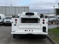 A 2013 Ford F-350 SD in white with a flatbed and utility features visible from the rear