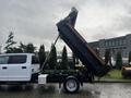 A white 2021 Ford F-550 dump truck with its bed raised for unloading materials