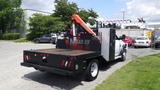 A 2014 RAM 5500 truck featuring a wooden flatbed and a mounted orange crane with a black protective cage on the side