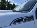 Close-up of a white 2013 Ford F-450 Super Duty with XLT badge on the side and droplets of water on the surface