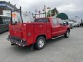 A red 2011 Ford F-250 SD with a utility bed and ladder racks visible in the foreground