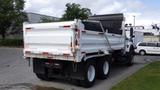 A white 2014 International 7500 dump truck with a large cargo bed and a tarpaulin cover is parked with its back facing the viewer