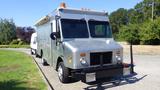 A silver 2005 Morgan Olson Workhorse delivery truck with a flat front and large windows is parked on a driveway