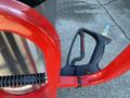 A close-up of the handle and trigger of a 2024 Magnum 4000 Hot Water Pressure Washer in red and black