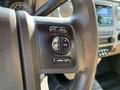 A close-up of the steering wheel controls of a 2013 Ford F-450 SD featuring buttons for media volume and selection