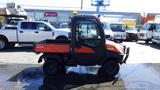 A 2013 Kubota RTV 1100 utility vehicle with an orange and black body featuring a cab and a bed for cargo designed for off-road use