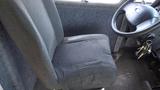 A worn driver's seat inside a 2011 Ford Econoline with a black steering wheel and a set of keys hanging from the ignition