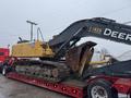 A 2014 John Deere 350G excavator with a yellow and black exterior is mounted on a red flatbed truck