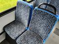 A pair of patterned bus seats in blue and gray fabric with a black handle on one seat