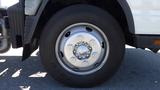 Close-up of a metallic wheel of a 2015 Mitsubishi Fuso FE with a six-bolt pattern and black tire tread