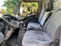 Interior of a 2015 Isuzu NPR showing two gray fabric seats and a dashboard with steering wheel and controls