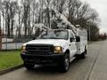 A white 2004 Ford F-450 SD utility truck with a mounted aerial lift and storage compartments on the sides