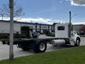 A 2014 Kenworth T370 truck with a white cab and black chassis is parked on a grassy area, featuring a prominent exhaust stack and large rear tires