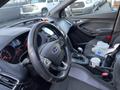 Interior view of a 2018 Ford Focus showing the steering wheel dashboard gear shift and car seat with items including a cup and a bag in the passenger area