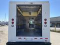 A 2012 Ford Econoline with open rear doors revealing an empty cargo area and seating for drivers and passengers