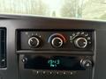 Dashboard controls of a 2009 Chevrolet Express featuring knobs for air conditioning and a display for radio station and time