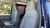 Interior view of a 2013 Ford Econoline showing two gray fabric seats with armrests and a partition behind the driver's seat