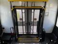 A 2015 Chevrolet Express wheelchair lift with a metal frame and yellow safety bars in the upright position