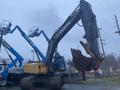 A 2014 John Deere 350G excavator with a large bucket attached raised in the air and tracks on the ground