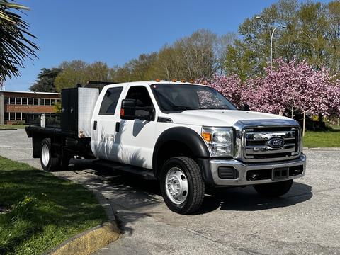 A 2016 Ford F-550 pickup truck with a white exterior and flatbed design is parked on a paved area