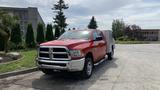 A red 2013 RAM 2500 truck with a silver utility bed parked on a paved surface