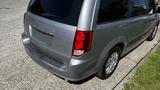 A silver 2016 Dodge Grand Caravan parked with a view of the rear and side, showcasing its hatchback design and taillights