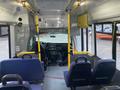 Interior view of a 2017 Chevrolet Express featuring rows of blue seats and a front dashboard with controls and visibility of the driver's area