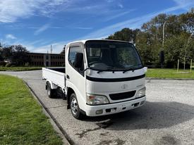 A white 2004 Toyota Toyoace flatbed truck parked with a clear view of its front and cabin