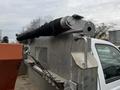 Close-up of a mechanical component attached to a gray concrete structure featuring a cylindrical roller with a black fabric covering and metal supports for a 2009 Ford F-550