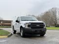 A white 2018 Ford F-150 parked with a black grille and chrome accents