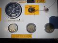 A control panel featuring dials and switches labeled for air compressor operation with gauges for RPM and pressure