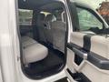 Interior view of a 2017 Ford F-150 showing the backseat area with light gray upholstery and a spacious layout