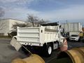 A 2015 International DuraStar 4300 dump truck with a white body and a wooden side rail attached to the bed