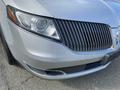 A silver 2013 Lincoln MKT featuring a distinctive grille and sleek headlights in the foreground