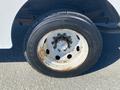 A close-up view of a tire mounted on a wheel with visible rust and wear on the rim and a solid black rubber surface