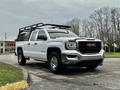 A white 2018 GMC Sierra 1500 pickup truck with a chrome grille and a black roof rack parked on a pavement