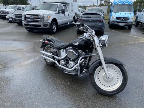 2008 Harley-Davidson FLSTFI motorcycle with a black body and chrome accents parked on a wet surface with a front wheel featuring a five-spoke design