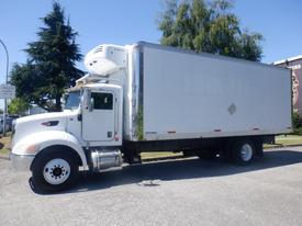 A white 2008 Peterbilt 335 truck with a refrigerated trailer and a diamond-shaped logo on the side